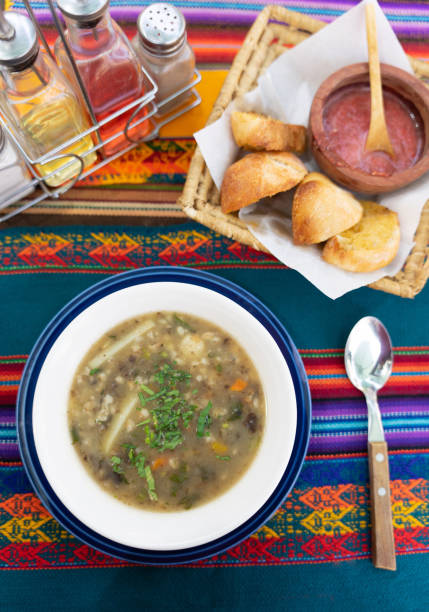 Traditional bolivian soup Chairo on a typical tablecloth, with condiments, chili and bread