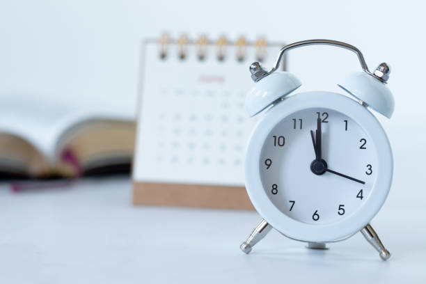 istock Alarm clock with calendar and holy bible book on white 2158015750