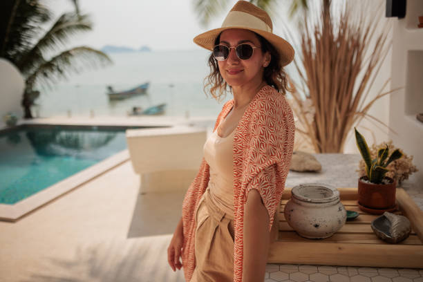 Woman enjoy a leisurely moment by the swimming pool at a luxurious villa on the beach.