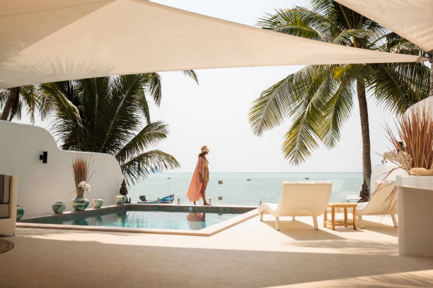 Vacation in paradise Woman enjoy a leisurely moment by the swimming pool at a luxurious villa on the beach. around the world stock pictures, royalty-free photos & images