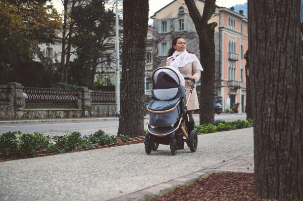 Young mother walking with stroller on a city sidewalk in autumn