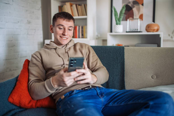 istock Connected Comfort: Young Man Engrossed in Smartphone at Home 2158027405