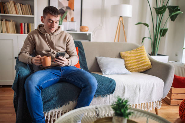 istock Connected Comfort: Young Man Engrossed in Smartphone at Home 2158028469