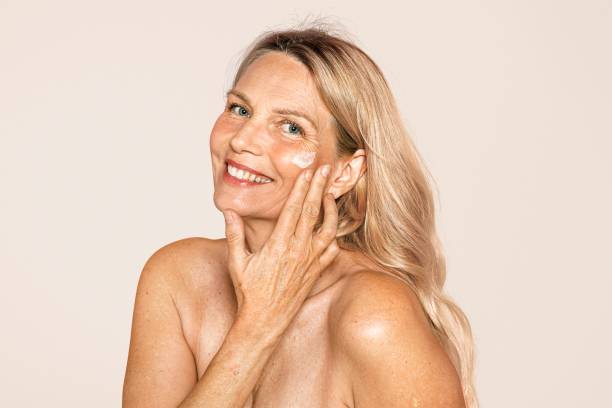 woman's anti aging skincare routine, pink background - produto antienvelhecimento imagens e fotografias de stock