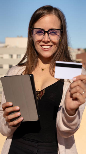 istock Young smiling woman paying by credit card on a digital tablet outdoors.Vertical 2158036951