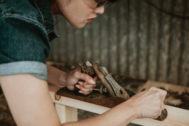 istock Female carpenter shaping lumber with a hand plane 2158038027