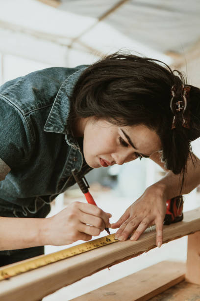 istock Female carpenter measuring the lumber 2158038028