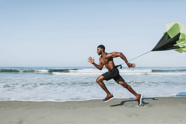 Fit man with a running parachute at the beach