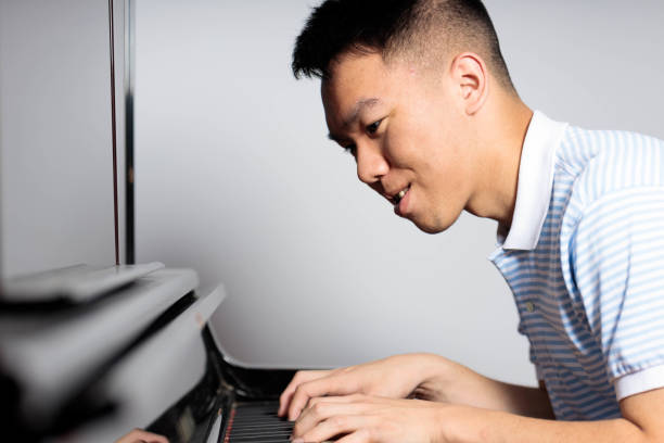 istock A teen boy playing and practicing on a piano at home 2158038674