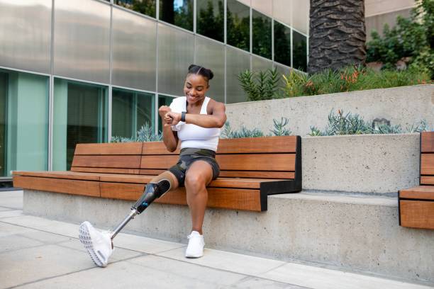 istock Woman with prosthetic leg looking at her smartwatch 2158040626