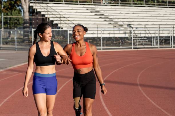 istock Two athletes laughing and talking to one another while on a running track 2158040683