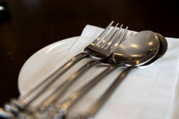 Plate fork spoon and paper napkin on the table. Close up