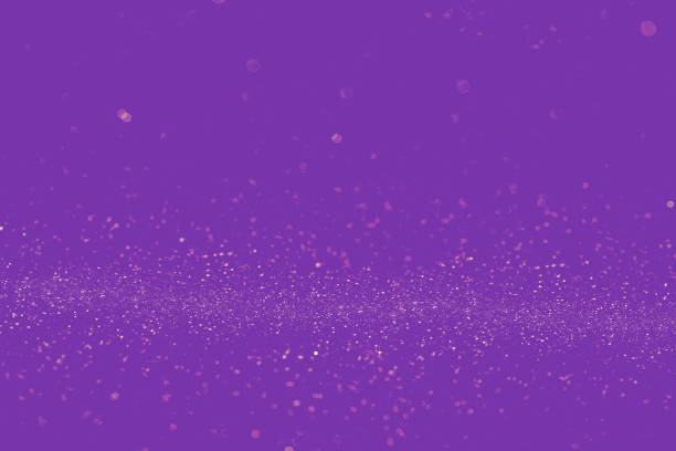 Gold shining particles on purple background. Abstract image