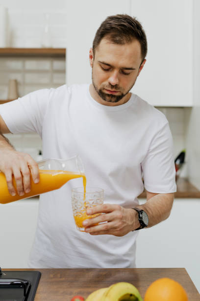 istock Man pouring orange juice into a glass 2158045004