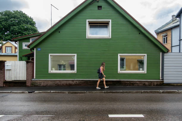 Tartu, Estonia June 8, 2024 A young woman walks past an old wooden green house in the Supilinn district
