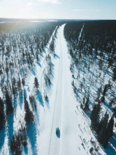 istock Vehicle on a snow covered road between the woods 2158046900