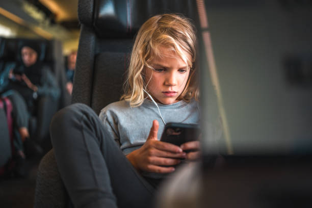 istock Blond-Haired Boy on Train with Smartphone and Earphones 2158047648