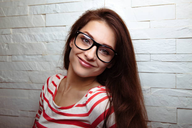 Happy positive fun woman in red eye glasses on studio white wall background with empty copy space. Closeup portrait
