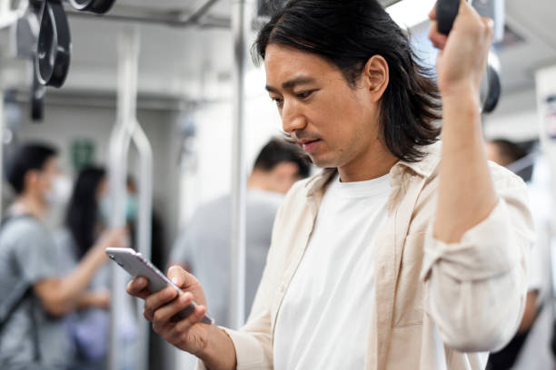 istock Japanese man scrolling on his phone while on the train 2158050980