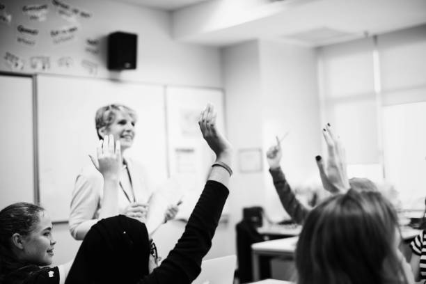Students with their hands up responding to their teacher