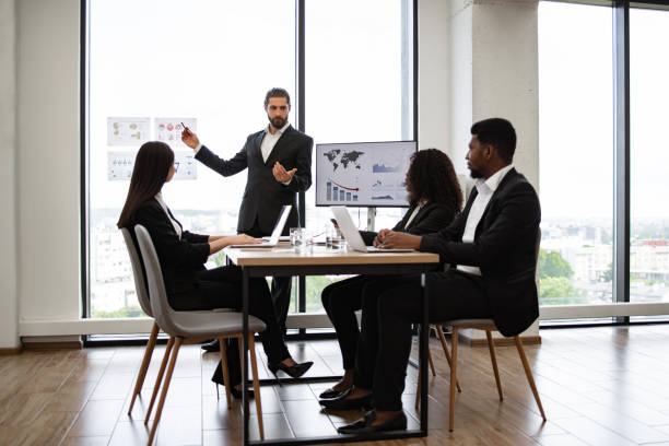 istock Business man presenting graphs to diverse colleagues in meeting room 2158051291