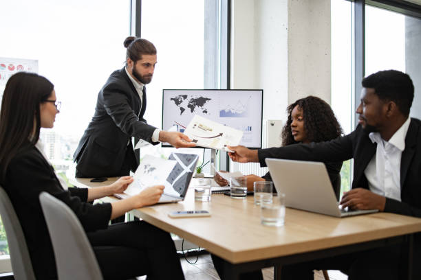 istock Businessman distributing documents during company meeting 2158051328