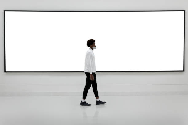 Man walking in front of a large billboard
