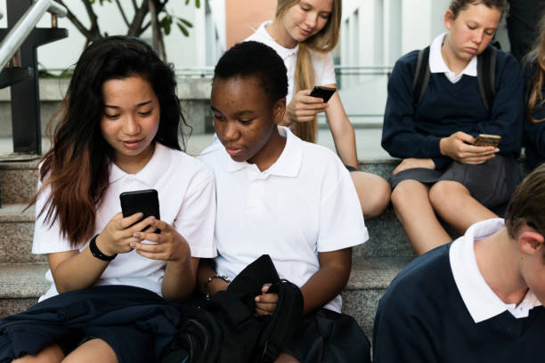 istock Group of students sitting at stairs and using digital devices 2158051630