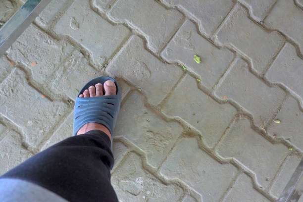 Closeup of rubber slipper worn by man.