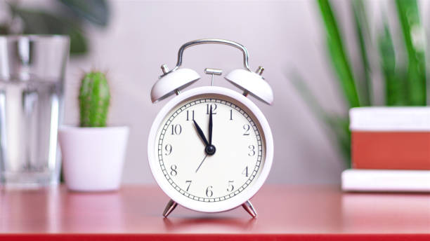 istock Classic white clock on a table. The clock hand points at 11 or 23 close up photo interior 2158055795