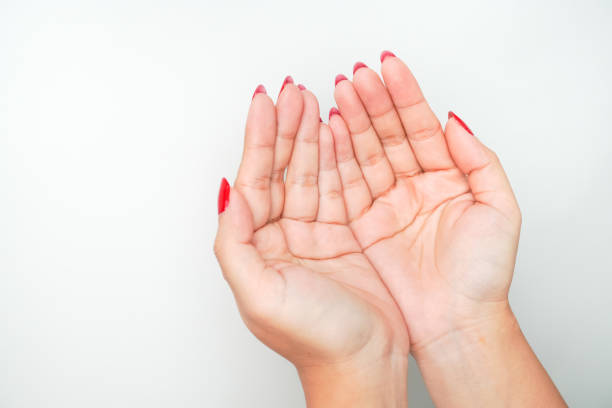 istock A woman's hand with bright red nail polish is making an open hand gesture and praying. Isolated on white background - cut out 2158057214