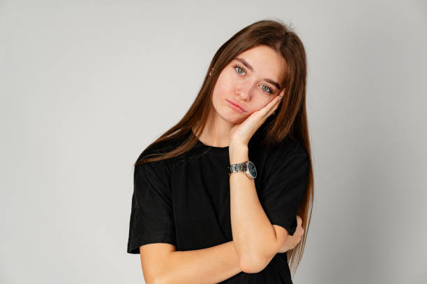 istock Bored Young Woman Leaning on Hand Against a Grey Background 2158057555