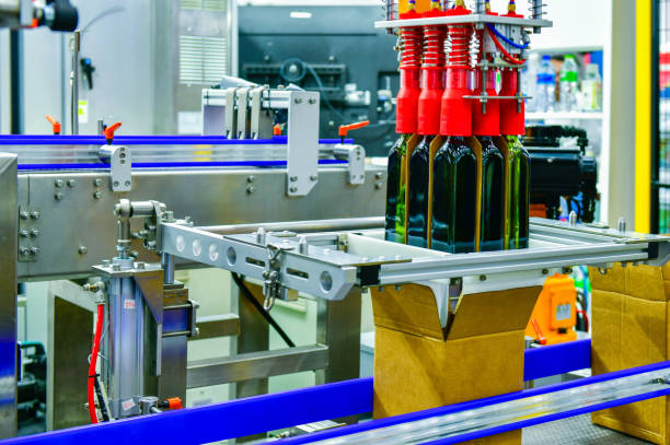 istock A robot arm is loading glass bottles into boxes on an automated industrial machine on a production line. 2158058833