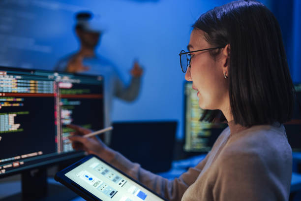 istock Asian UX designer works on a tablet while a colleague tests a VR application ,integration of user experience design and virtual reality development in a modern tech workspace 2158059131