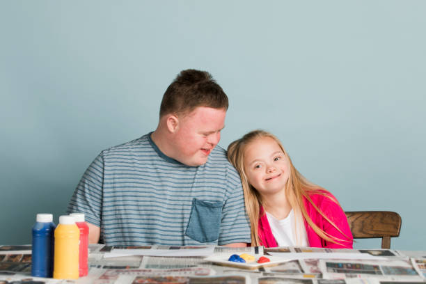 istock Cute siblings with down syndrome playing with paint 2158059243