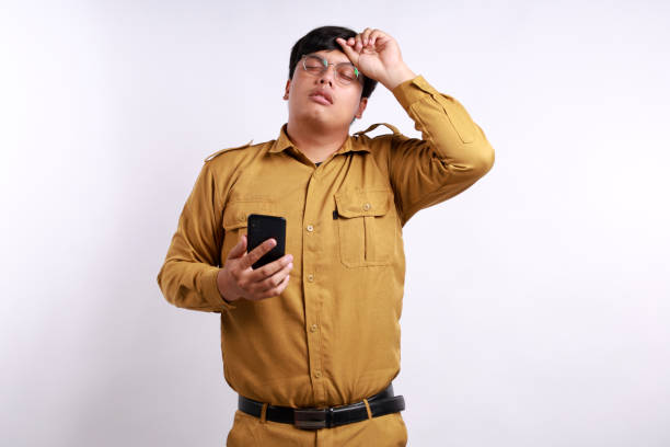 istock Stressed Indonesian civil servant man holding cell phone while having headache 2158059792
