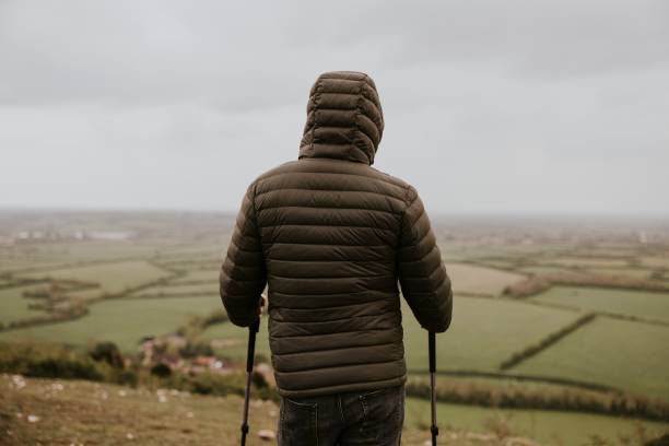 istock Man wearing jacket, holding hiking pole, rear view 2158061991