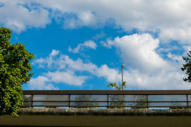 a bridge with a clear glass railing and a cloudy sky in the background