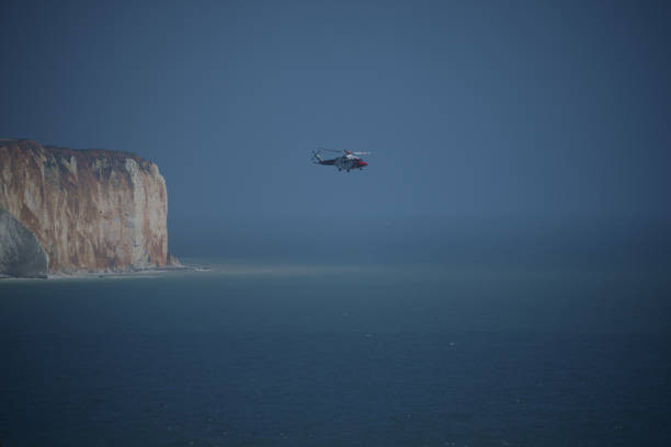 A rescue helicopter fly past the cliffs at Saeford Head, Sussex, English Channel, Newhaven