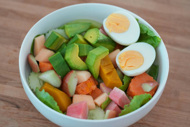 Mixed fruit and vegetable salad on a wooden table.