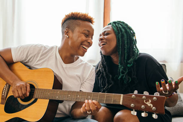 Happy lesbian couple playing the guitar and singing