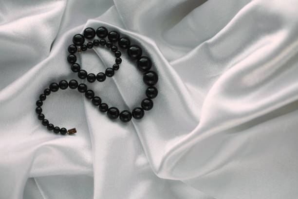 istock Stylish black pearls on white silk 2158070388