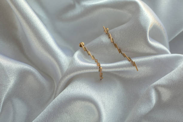 istock Gold earrings on white silk 2158070447