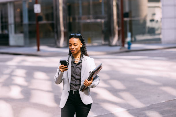 istock Businesswoman Smiling While Using Phone on City Street 2158071820