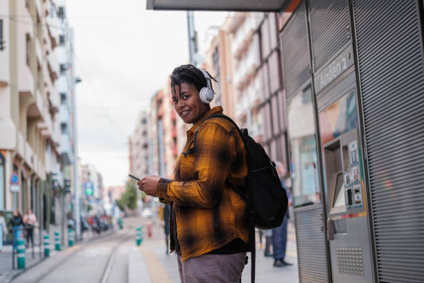 istock Young man in yellow checkered t-shirt using smartphone while waiting for the tram. Concept: public transport, lifestyle, urbanstyle 2158074450