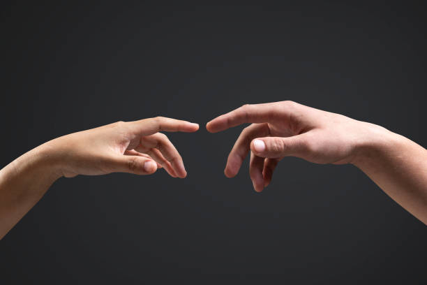 istock Human hands reaching for each other black background 2158074498
