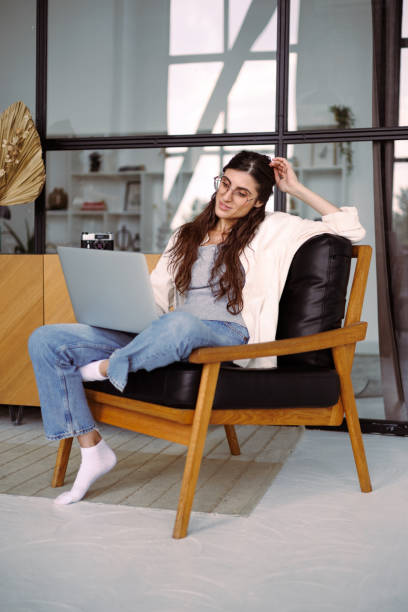istock Joyful female freelancer using laptop on armchair at home 2158074934