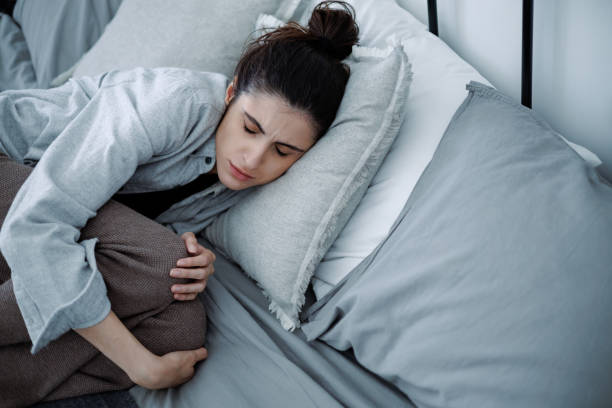 istock Brunette woman with mental problem touching knees while lying on bed at home 2158077238