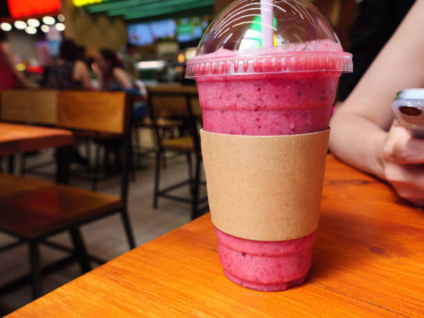 istock Pastic cup with a pink smoothie sits on a wooden table in the cafe 2158077844