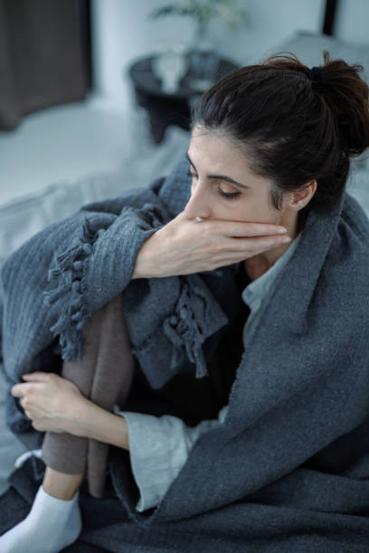 istock Frustrated brunette woman in blanket touching face while sitting on bed at home 2158078888